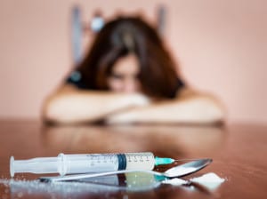 Syringe and drugs with out of focus female addict
