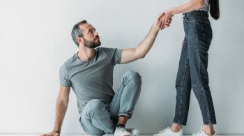 woman giving man sitting on floor hand to stand up