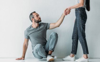 woman giving man sitting on floor hand to stand up