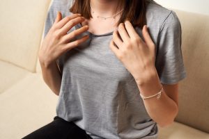 Teenage girl practicing EFT or emotional freedom technique - tapping on collarbone point, indoors